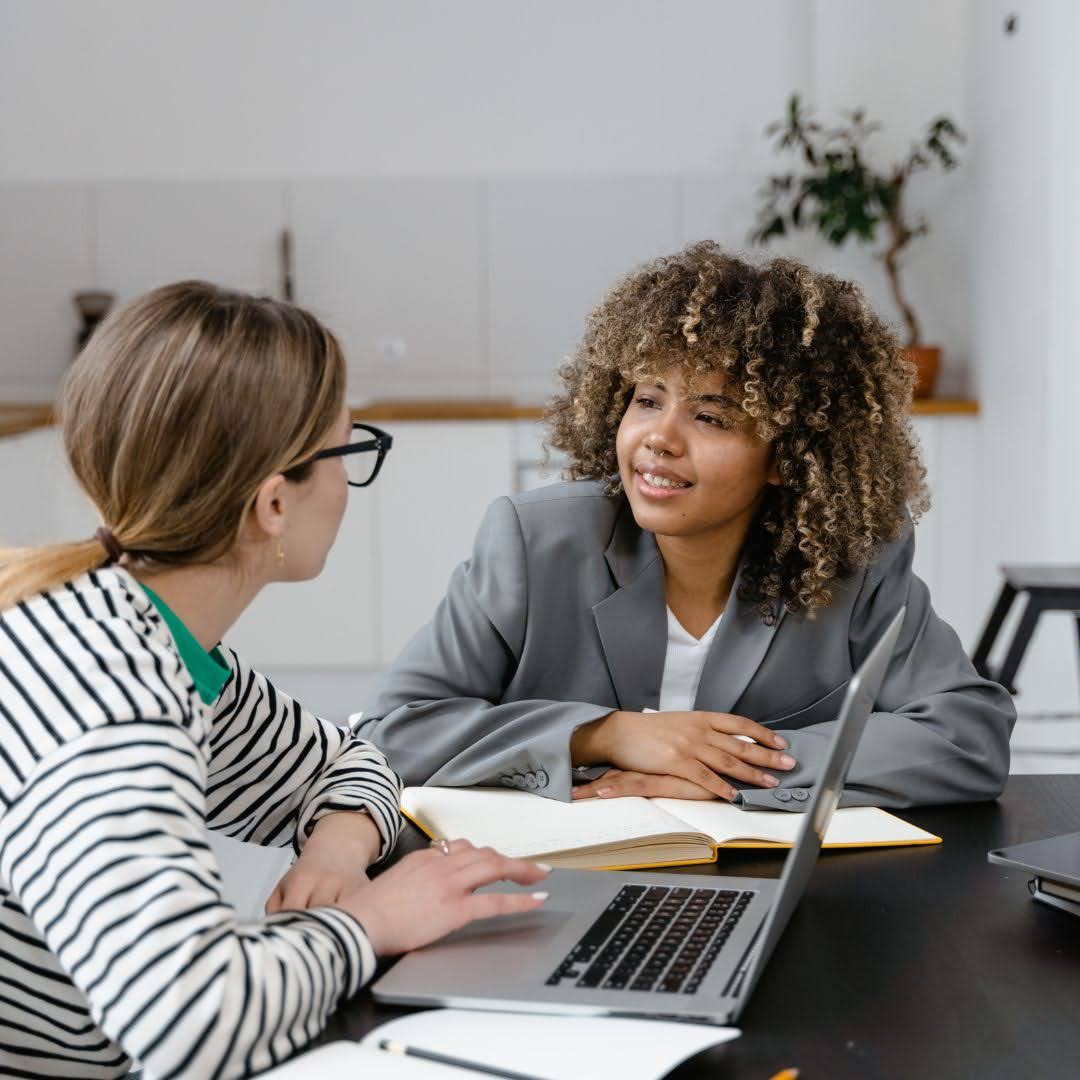 Two people having a supportive conversation with a notebook and laptop, relevant to Decider 32 Skills emotional wellbeing training in Australia.