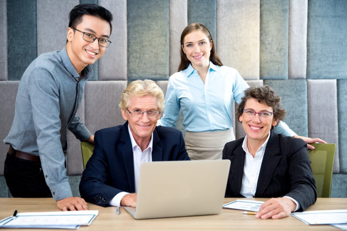 Managers and leaders gathered around a laptop, representing workplace wellbeing and mental health training in Australia.